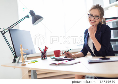 A young girl sits at a table and holds a pencil in her hand. A young girl sits at a table and holds a pencil in her hand. 42735619