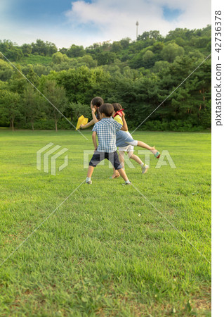 Children play paper airplanes in the park. 42736378