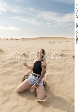 Kneeling woman in the sand Kneeling woman in the sand 42737584