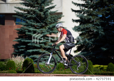 Male cyclist training on street edge Male cyclist training on street edge 42737591