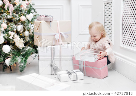 Cute baby and christmas gifts. Little child having fun near Christmas tree in living room. Loving 42737813