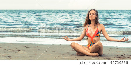 Young woman practices yoga on the beach in summer. Young woman practices yoga on the beach in summer. 42739286