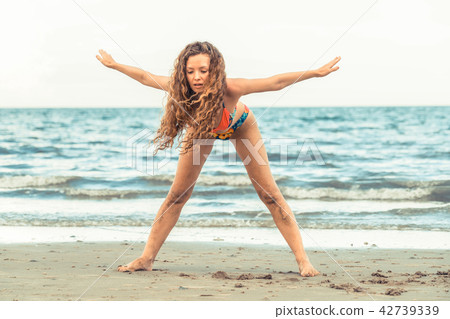 Young woman practices yoga on the beach in summer. 42739339