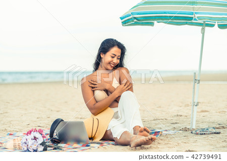 Plus size young woman sitting on the beach. 42739491
