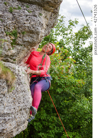 Photo of athlete woman in helmet clambering over rock Photo of athlete woman in helmet clambering over rock 42743326