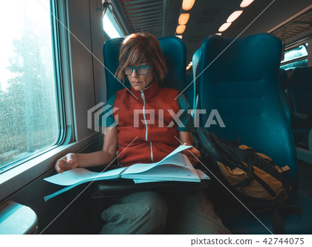 Woman using smart phone traveling by train Woman using smart phone traveling by train 42744075