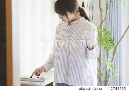 A woman watching a smartphone at the window side A woman watching a smartphone at the window side 42745265