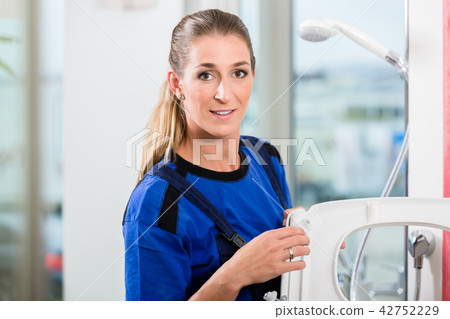 Female maintenance worker checking the quality of a toilet seat Female maintenance worker checking the quality of a toilet seat 42752229