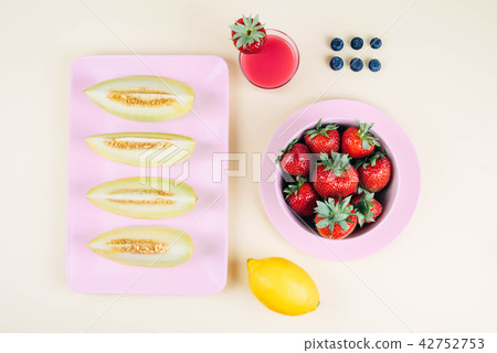 Fresh strawberries in bowl and melone on pastel yellow background. 42752753