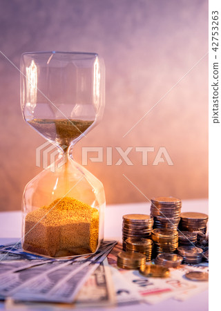 Hourglass and currency on table, Time Investment Hourglass and currency on table, Time Investment 42753263