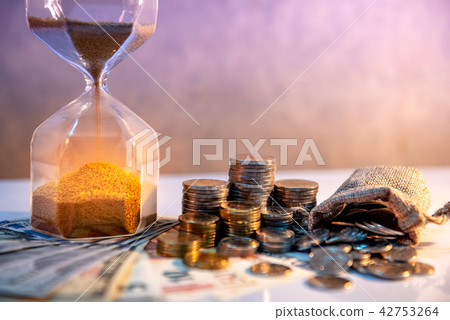Hourglass and currency on table, Time Investment Hourglass and currency on table, Time Investment 42753264