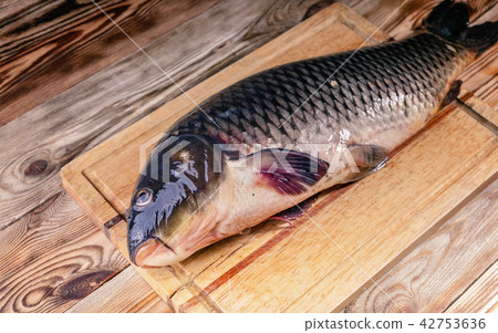 Big Carp on a cutting board on a wooden table. 42753636
