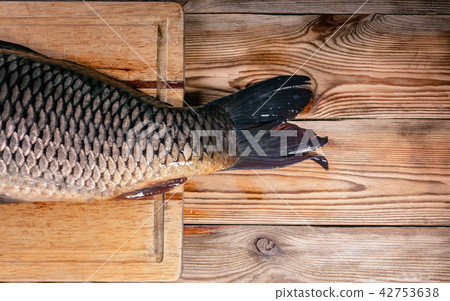 Tail big carp on a cutting board on a wooden table 42753638