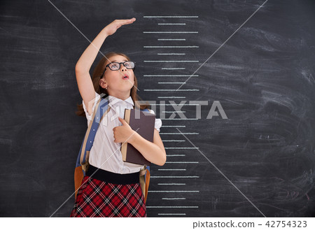 Kid measures growth on background of blackboard Kid measures growth on background of blackboard 42754323