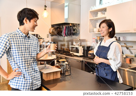 A male guest who receives coffee from a female clerk at a cafe A male guest who receives coffee from a female clerk at a cafe 42758153