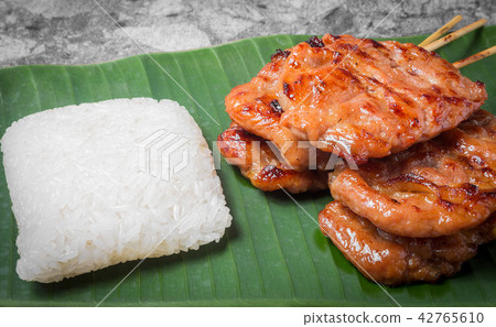 Grilled pork with sticky rice on banana leaf. 42765610