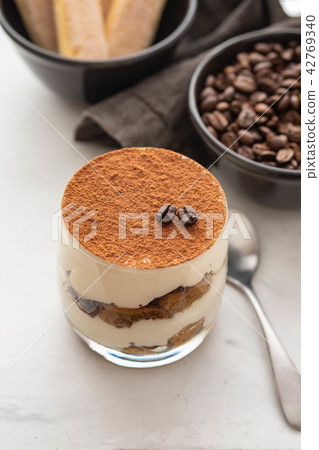 Traditional Italian dessert tiramisu in a glass on a white stone background. Copy space. Traditional Italian dessert tiramisu in a glass on a white stone background. Copy space. 42769340