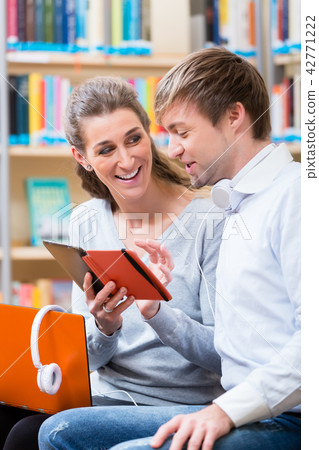 Woman and man with laptop and phone in library 42771222