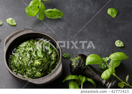 Basil pesto sauce in iron mortar, close up view Basil pesto sauce in iron mortar, close up view 42771423
