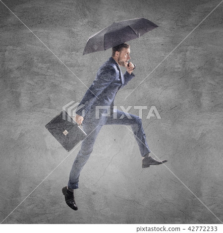 Businessman running with umbrella and briefcase. 42772233