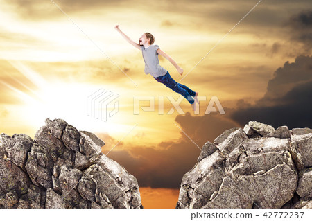 Little cute girl flying like a supergirl from one rock to another. 42772237