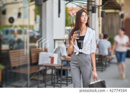 Stylish student walking in downtown drinking coffee. 42774584