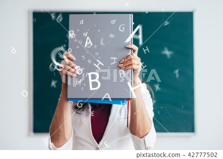 Female student standing near blackboard with book Female student standing near blackboard with book 42777502
