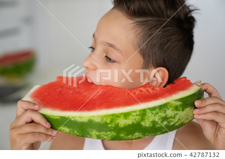 Caucasian boy with expressive eyes, taking a bite of a juicy watermelon 42787132
