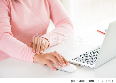 Woman holding her wrist pain from using computer Woman holding her wrist pain from using computer 42794203