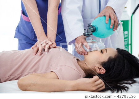 Hands of doctors giving cardiac massage to a woman 42795156