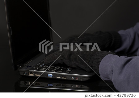 Hacker hand in glove working on laptop. Hacker hand in glove working on laptop. 42799720