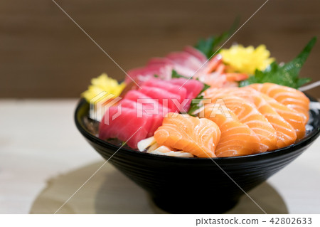 Mixed sliced fish sashimi on ice in black bowl. Mixed sliced fish sashimi on ice in black bowl. 42802633