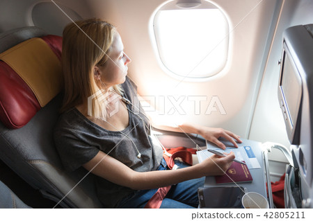 Casual woman flying on commercial passengers airplane, filling in immigration form. 42805211