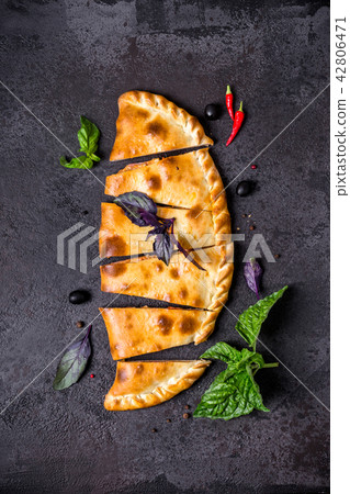 Pizza calzone is cut into pieces on black table 42806471