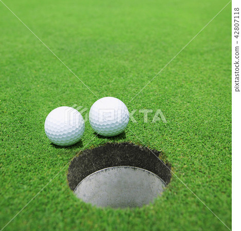 The balls at the hole on the golf course 42807118