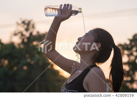 young woman drinking water after jogging 42809159