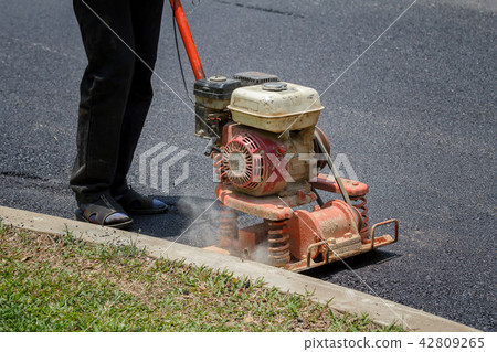 Worker uses vibratory plate compactor 42809265