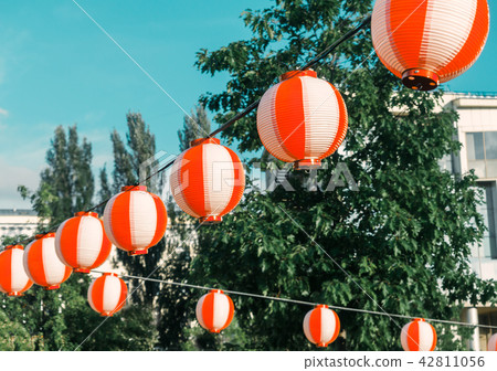 Paper red-white japanese lanterns Chochin hanging on blue sky background Paper red-white japanese lanterns Chochin hanging on blue sky background 42811056