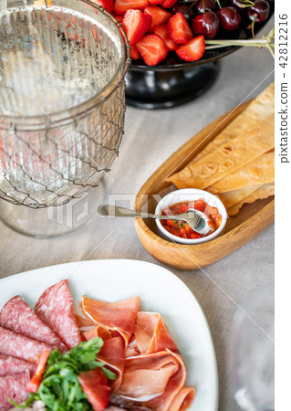 Food tray with delicious salami, pieces of sliced ham, sausage. Cutting sausage and cured meat on a Food tray with delicious salami, pieces of sliced ham, sausage. Cutting sausage and cured meat on a 42812216