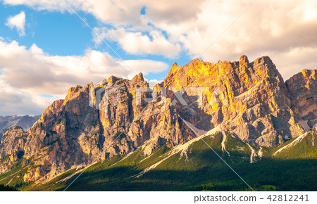 Rocky ridge of Pomagagnon Mountain above Cortina d'Ampezzo with green meadows and blue sky with Rocky ridge of Pomagagnon Mountain above Cortina d'Ampezzo with green meadows and blue sky with 42812241