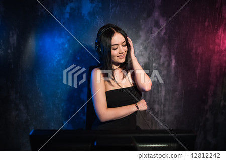 Colorful portrait in blue and dark ligth of a young DJ woman enjoying a night party 42812242