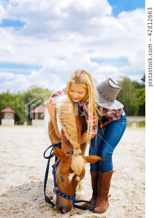 Kind-hearted schoolgirl playing with little cute pony with braid 42812663