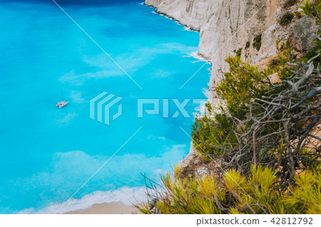 Lonely catamaran yacht in blue bay of Navagio beach. Azure turquoise sea water pattern near paradise Lonely catamaran yacht in blue bay of Navagio beach. Azure turquoise sea water pattern near paradise 42812792