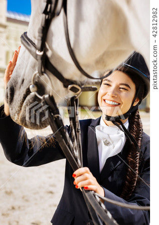 Dark-eyed smiling female rider coming to race track on her day off Dark-eyed smiling female rider coming to race track on her day off 42812982