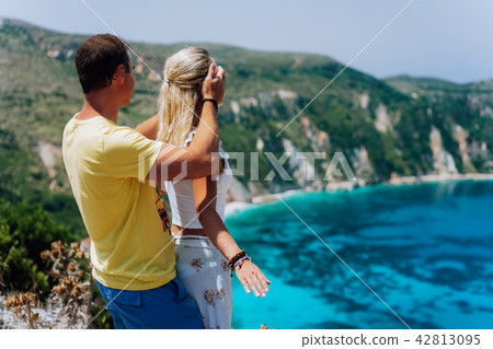 Birthday gift. Young man closing hes girlfriend eyes in front of gorgeous seascape panorama of blue 42813095