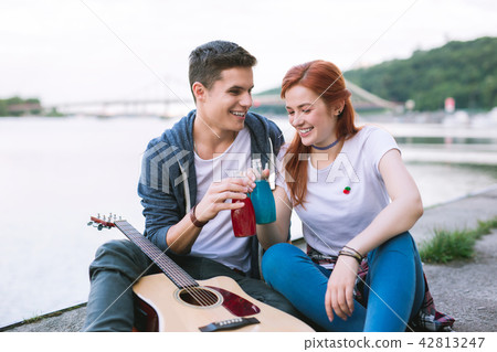 Positive happy couple sitting near the river Positive happy couple sitting near the river 42813247