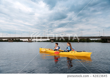 Sport couple holding red and yellow paddles rowing in canoe 42813645