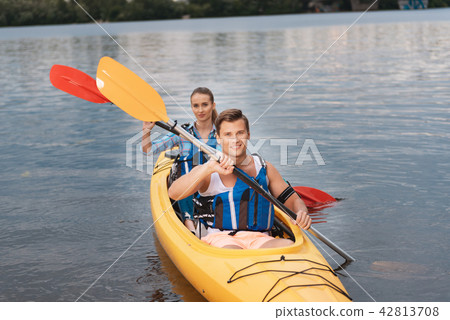 Smiling blue-eyed man rowing in kayak along with his girlfriend 42813708