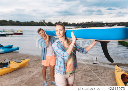 Young beautiful couple holding blue boat preparing for river ride 42813973