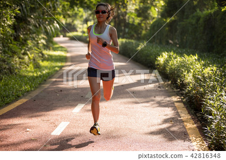 Fitnesswoman runner running on morning park road   42816348